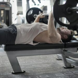 A man performing an intense bench press workout in a modern gym, showcasing strength and focus.
